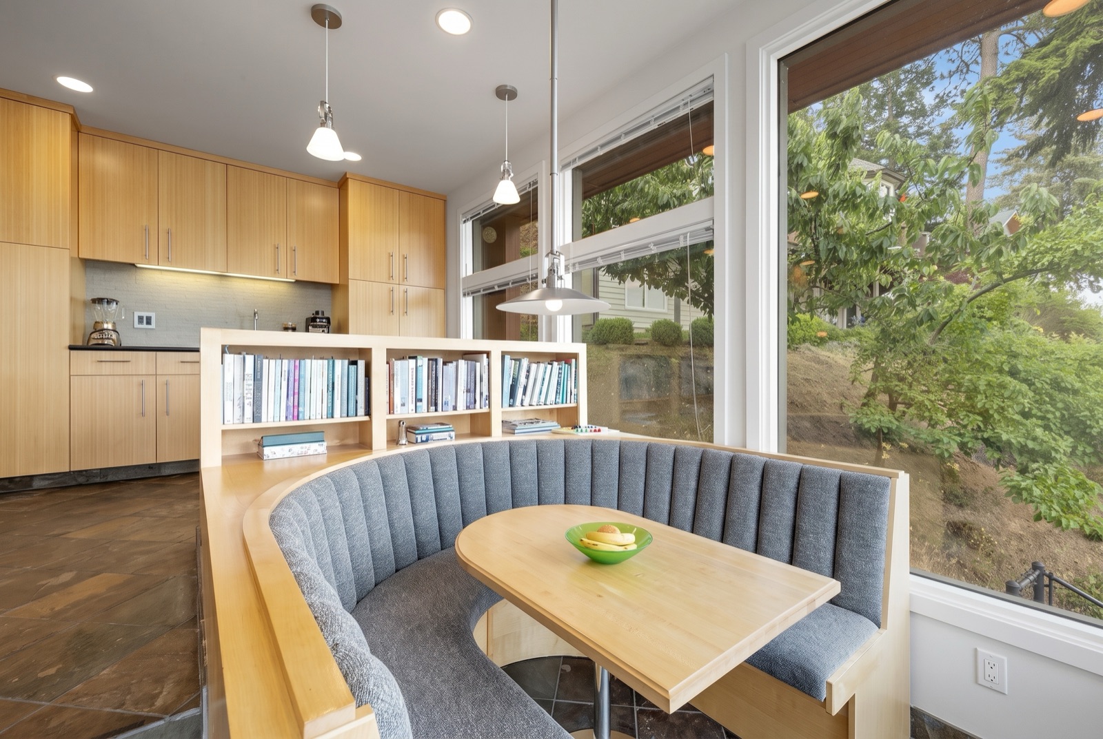 Built-in breakfast nook with a curved upholstered bench and warm wood cabinetry beside a bright window