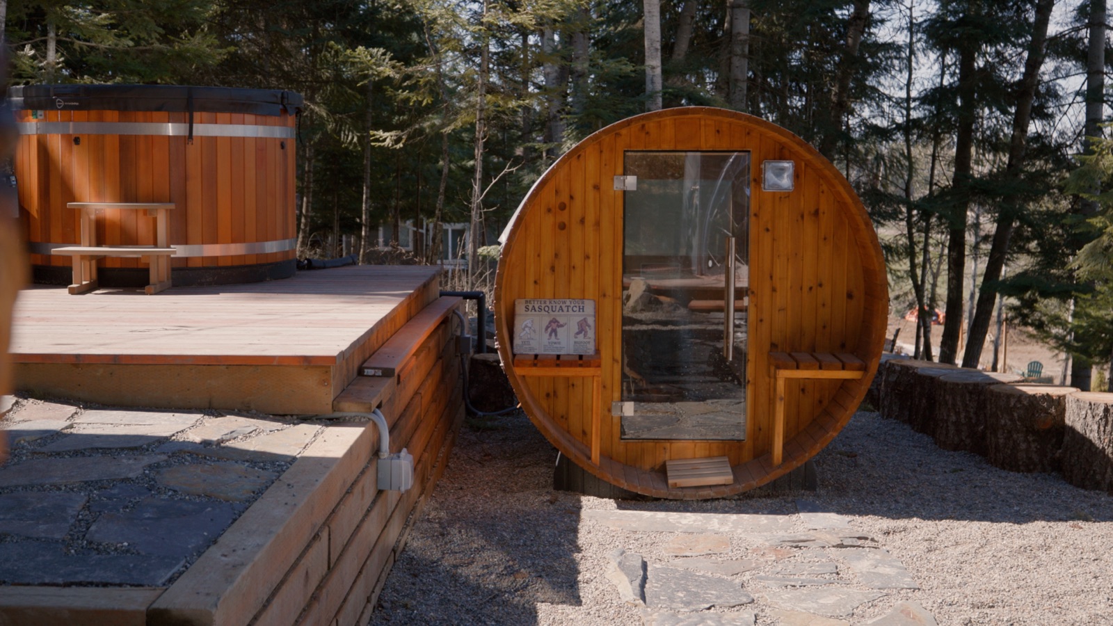 Cedar barrel sauna and round cold-plunge tub on a timber deck among pines